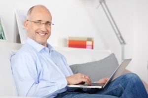 middle aged man using a laptop and smiling