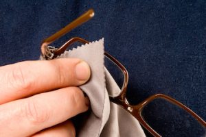 close up of someone cleaning glasses with a lens cloth